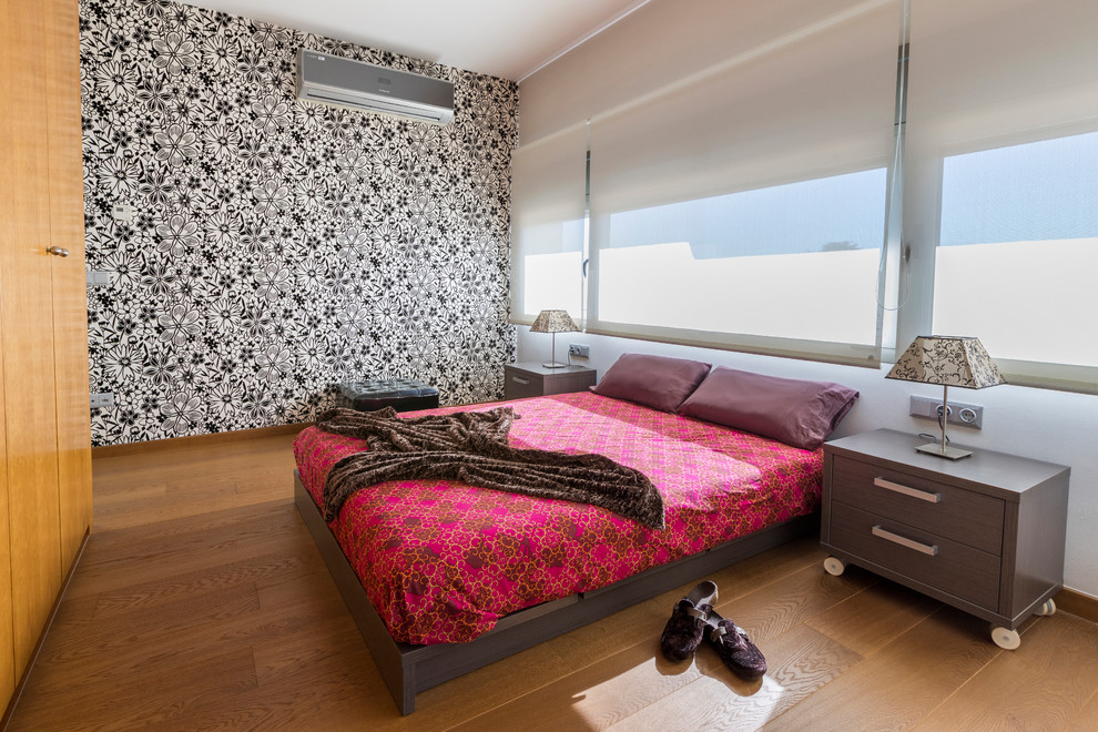 Immagine di una grande camera degli ospiti minimal con pareti multicolore, pavimento in legno massello medio, nessun camino e pavimento marrone