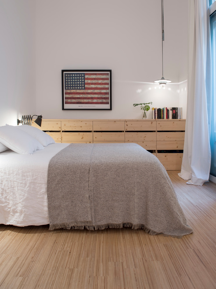 Diseño de dormitorio principal industrial de tamaño medio con paredes blancas, suelo de madera clara y suelo beige