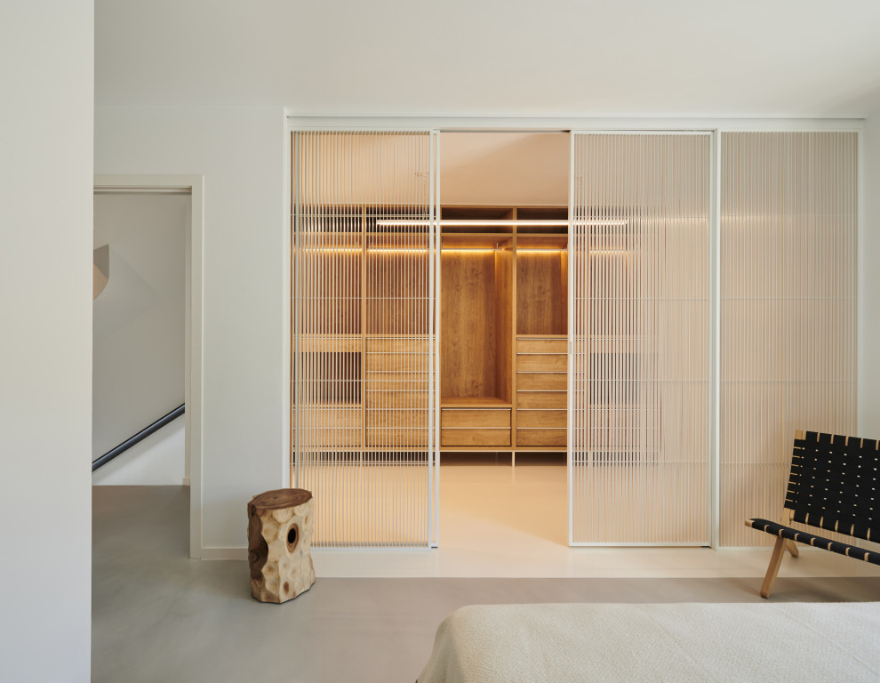 Imagen de dormitorio tipo loft minimalista de tamaño medio con paredes blancas, suelo de cemento y suelo gris