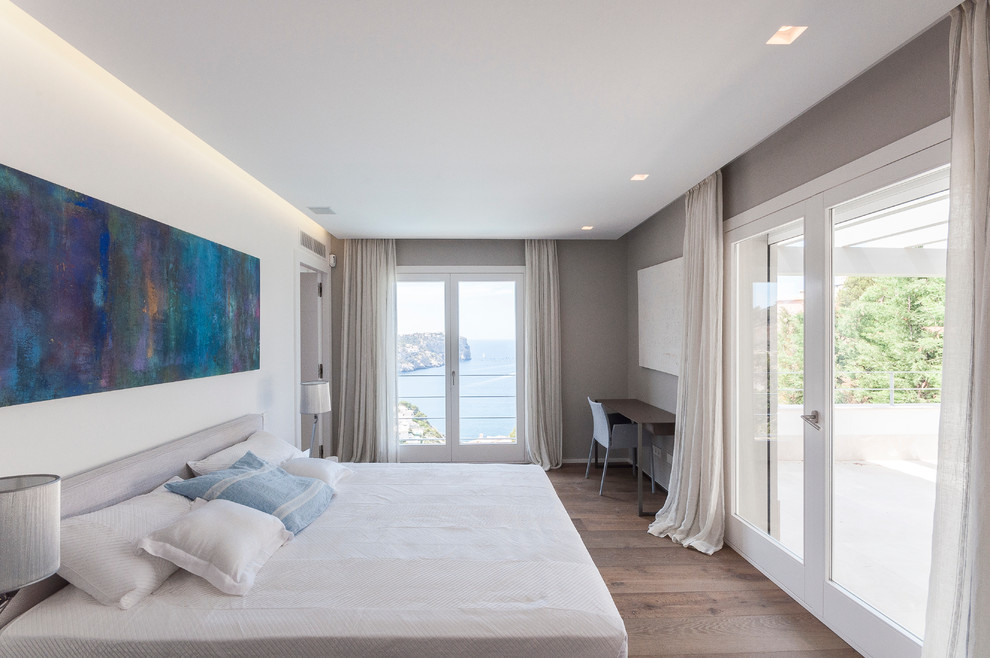 Imagen de dormitorio principal minimalista grande sin chimenea con paredes blancas y suelo de madera en tonos medios
