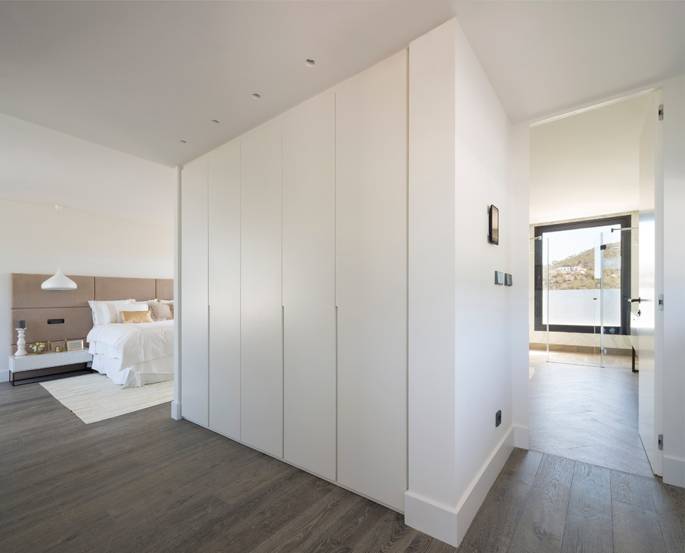 Aménagement d'une très grande chambre parentale contemporaine avec un mur blanc, un sol en bois brun et aucune cheminée.