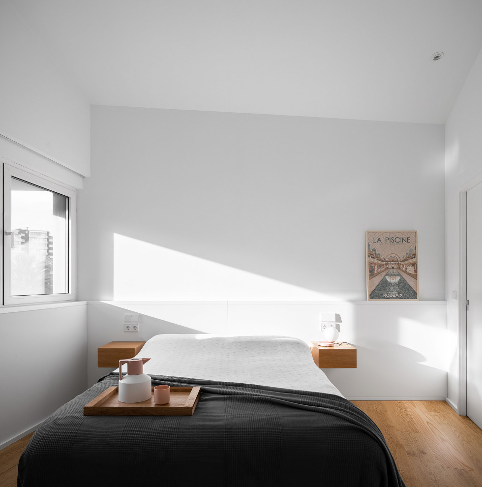 Diseño de dormitorio moderno con paredes blancas, suelo de madera en tonos medios y suelo marrón