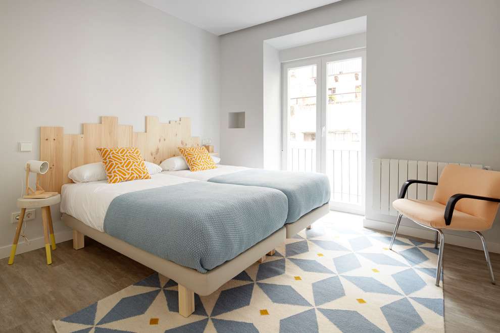Immagine di una camera da letto design con pavimento in legno massello medio, pareti grigie e pavimento marrone