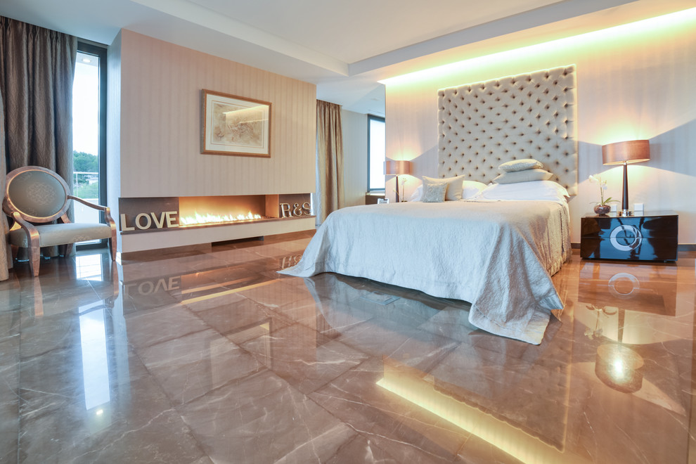 Modelo de dormitorio principal moderno con paredes beige, chimenea lineal y suelo beige
