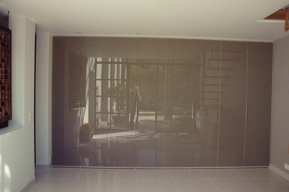 Ispirazione per un ampio armadio o armadio a muro unisex design con ante di vetro, pavimento con piastrelle in ceramica e ante grigie