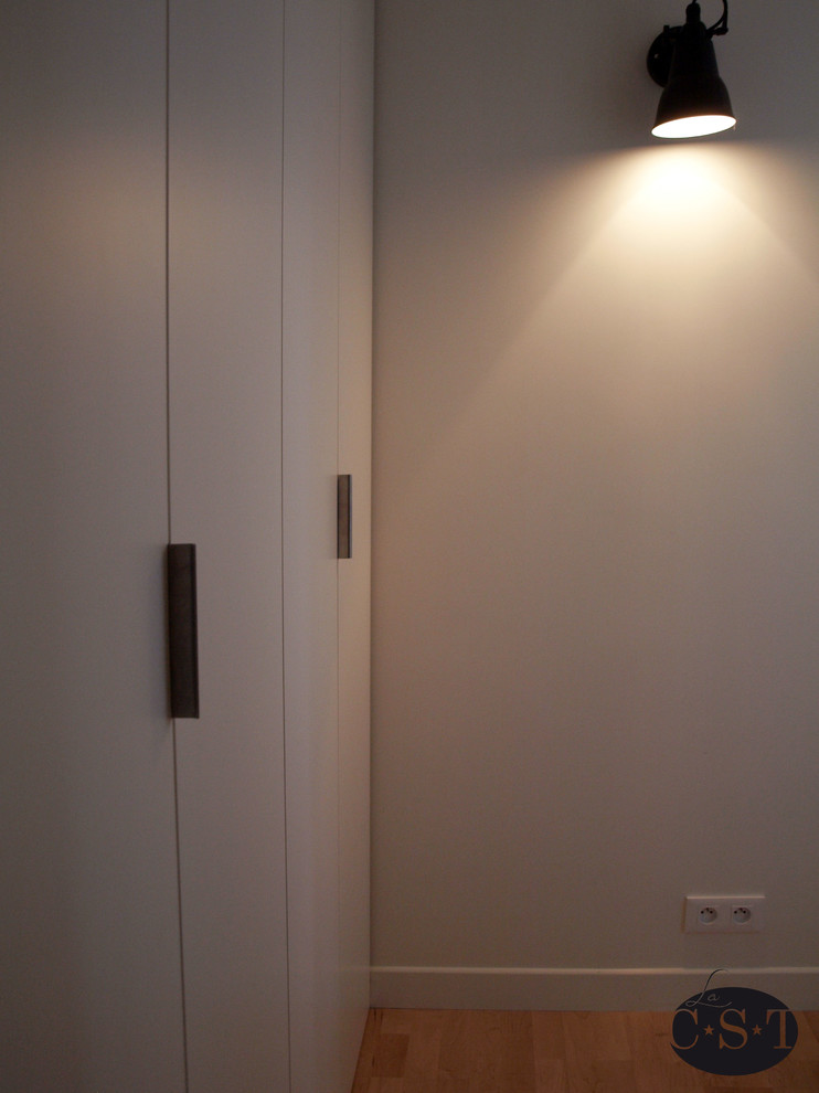 Foto di un piccolo armadio o armadio a muro unisex contemporaneo con ante a filo, ante bianche e parquet chiaro