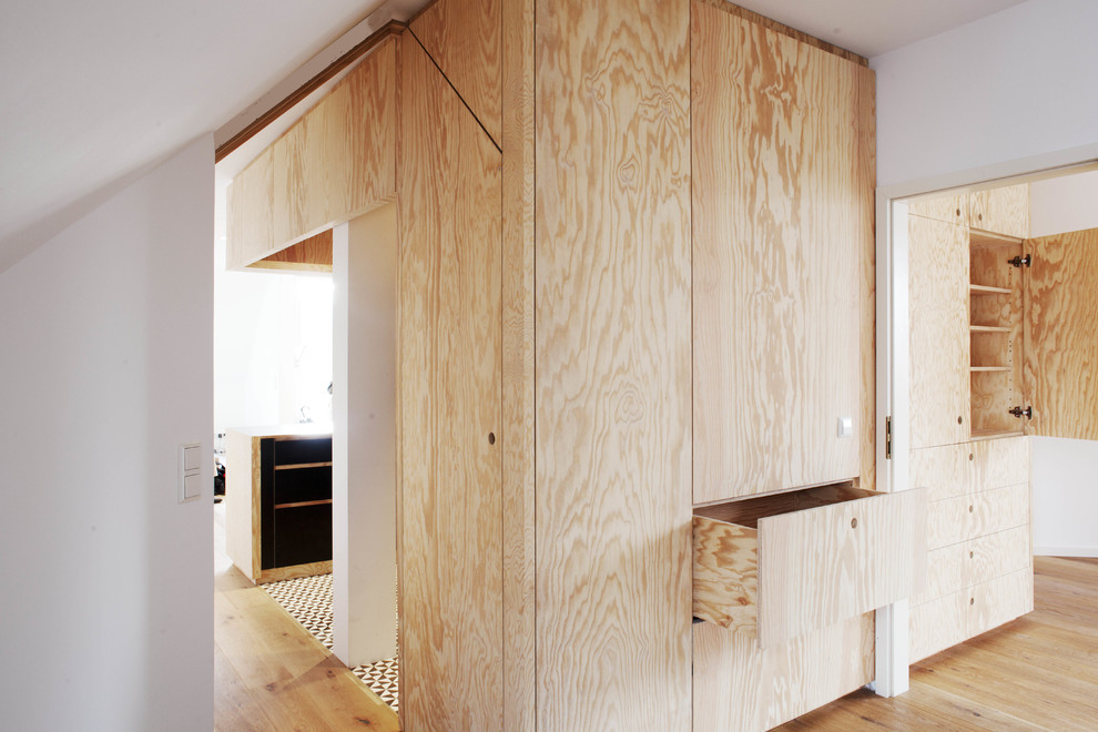 Foto di un armadio o armadio a muro unisex design con ante lisce, ante in legno chiaro, parquet chiaro e pavimento beige