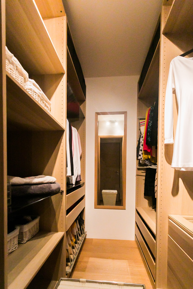 Ejemplo de armario vestidor unisex contemporáneo con puertas de armario de madera clara y suelo de madera clara