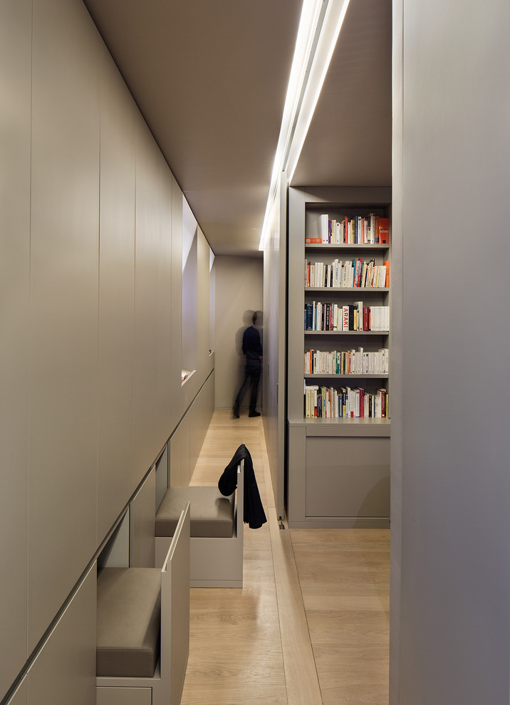 Cette image montre un grand dressing room design pour un homme avec des portes de placard grises et parquet clair.