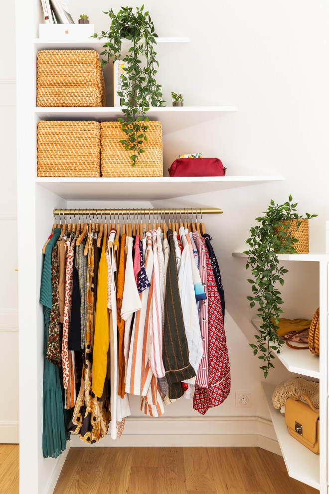 Ejemplo de armario vestidor de mujer romántico pequeño con armarios abiertos, puertas de armario blancas, suelo de madera clara y suelo marrón