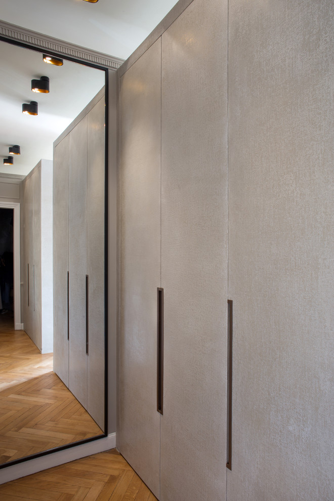 Diseño de armario unisex actual grande con puertas de armario beige y suelo de madera clara