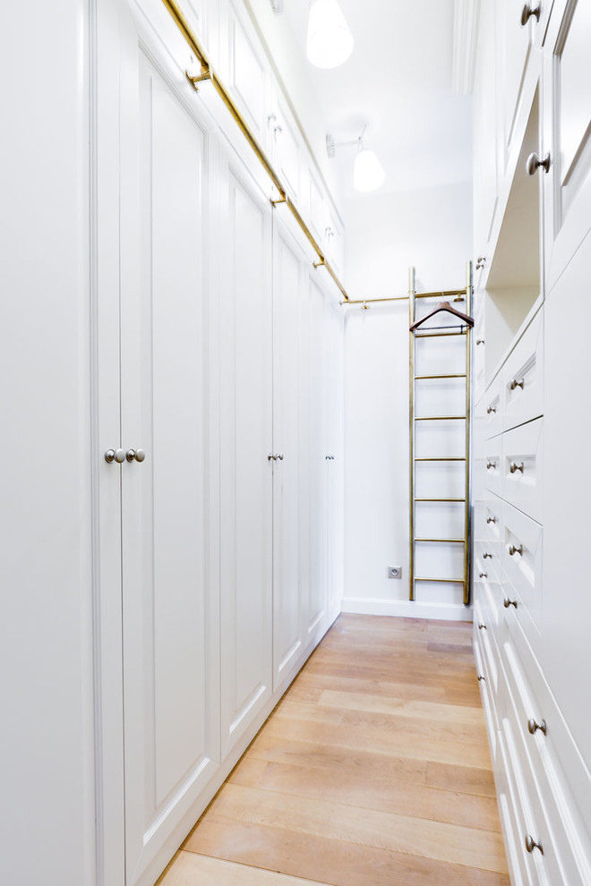 Ejemplo de armario vestidor unisex clásico renovado pequeño con armarios con paneles empotrados y suelo de madera clara