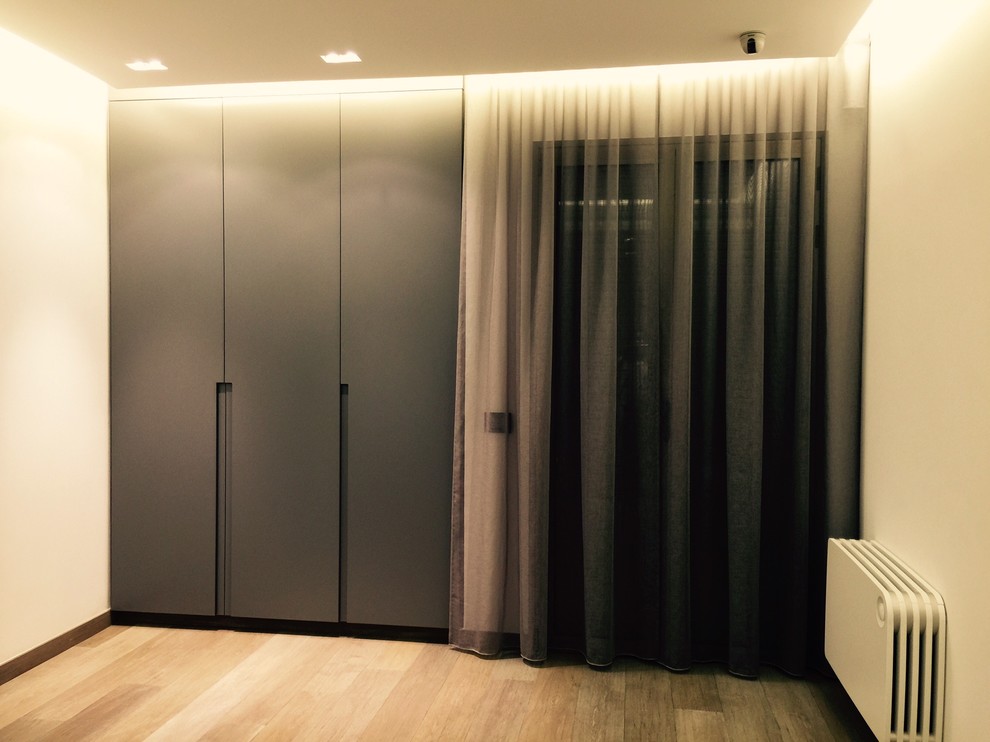 Imagen de armario de hombre actual de tamaño medio con suelo de madera clara, suelo beige, armarios con rebordes decorativos y puertas de armario grises