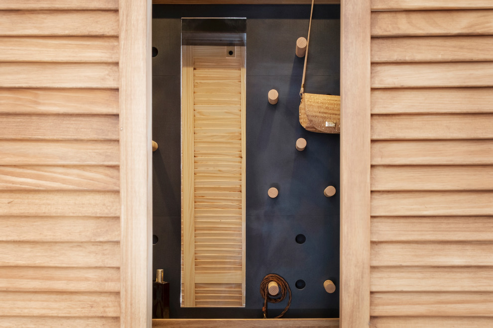 Réalisation d'un petit dressing room urbain en bois clair neutre avec un placard à porte persienne, parquet clair et un sol beige.