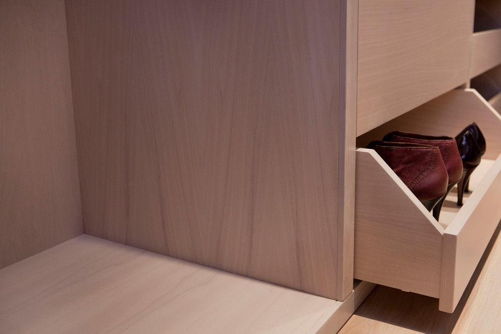 Réalisation d'un petit dressing room design en bois clair pour une femme avec un placard sans porte, parquet clair et un sol marron.