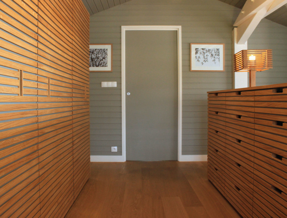 Пример оригинального дизайна: большая гардеробная комната унисекс в современном стиле с светлыми деревянными фасадами, светлым паркетным полом и плоскими фасадами