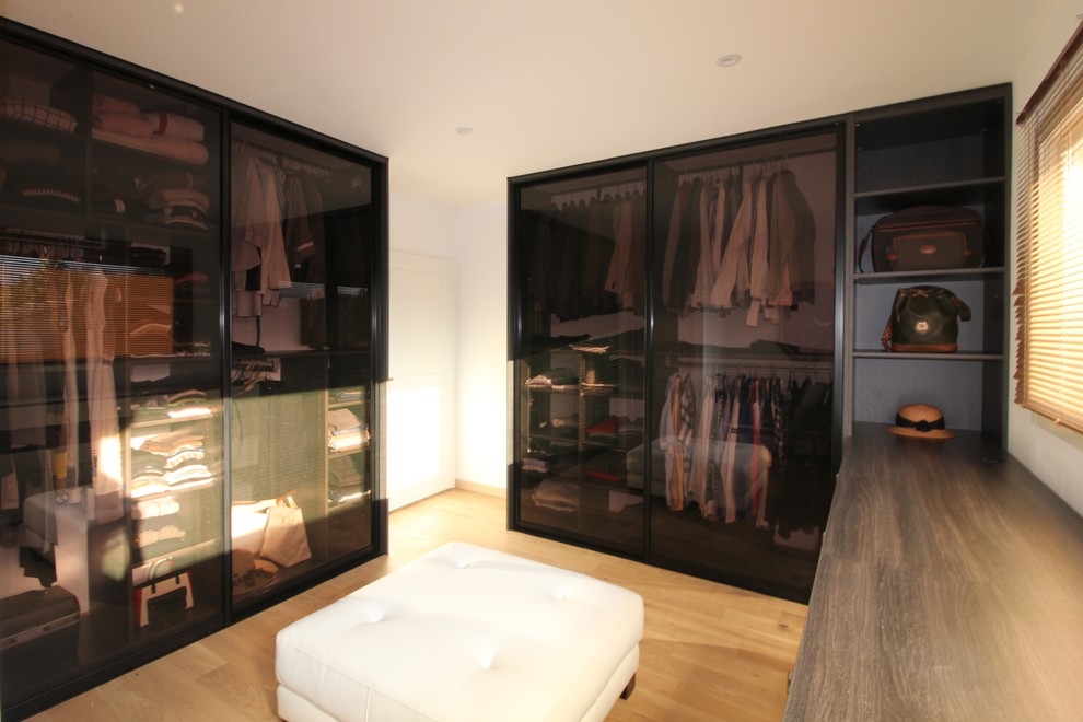 Inspiration för stora moderna walk-in-closets för könsneutrala, med luckor med glaspanel, skåp i mörkt trä, ljust trägolv och beiget golv