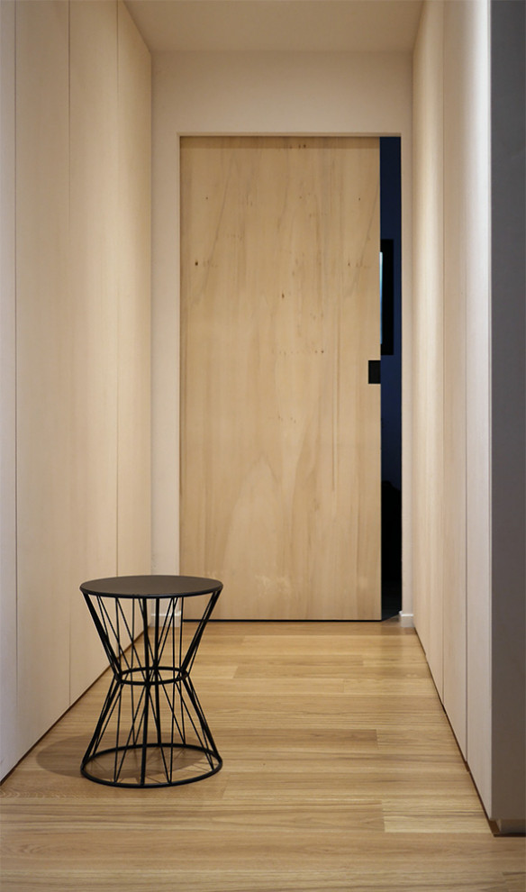Diseño de vestidor unisex contemporáneo de tamaño medio con puertas de armario negras, armarios con paneles lisos, suelo de madera clara y suelo marrón
