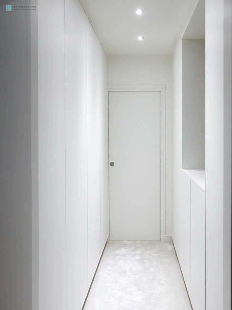 Diseño de vestidor unisex moderno de tamaño medio con armarios con rebordes decorativos, puertas de armario blancas y moqueta