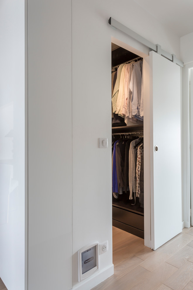 Photo of a small contemporary gender neutral dressing room in Other with open cabinets, light hardwood flooring and beige floors.