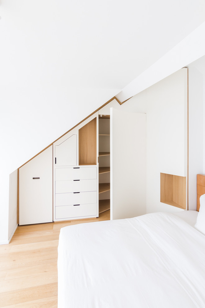 Imagen de armario unisex contemporáneo grande con armarios con rebordes decorativos, puertas de armario blancas, suelo de madera clara y suelo beige