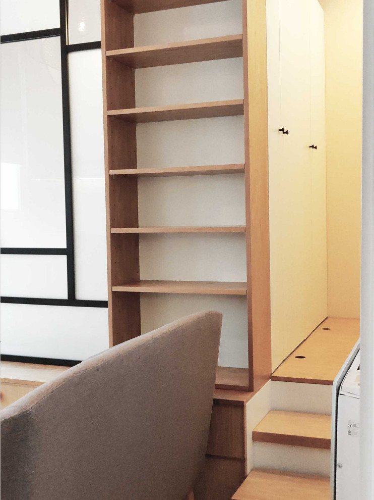 Immagine di una piccola cabina armadio unisex minimal con ante a filo, ante bianche, parquet chiaro e pavimento beige