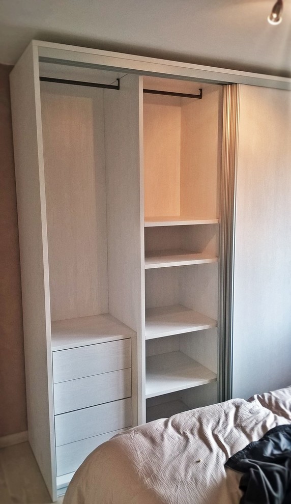 Photo of a medium sized contemporary gender neutral walk-in wardrobe in Lyon with flat-panel cabinets, light wood cabinets, light hardwood flooring and beige floors.