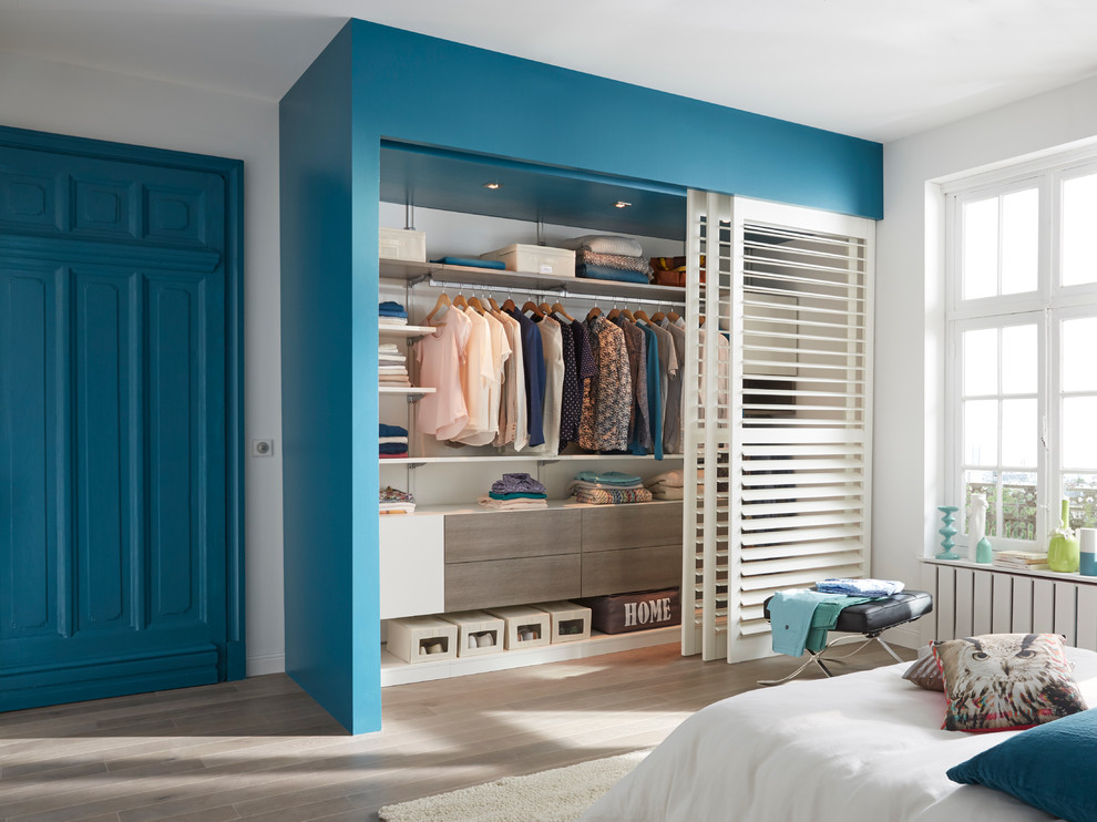 Foto de armario unisex minimalista de tamaño medio con suelo de madera clara
