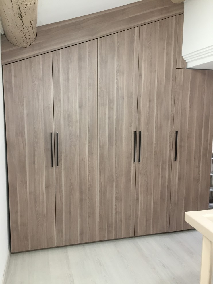 Imagen de armario unisex contemporáneo de tamaño medio con armarios con paneles lisos, puertas de armario de madera oscura y suelo de madera clara