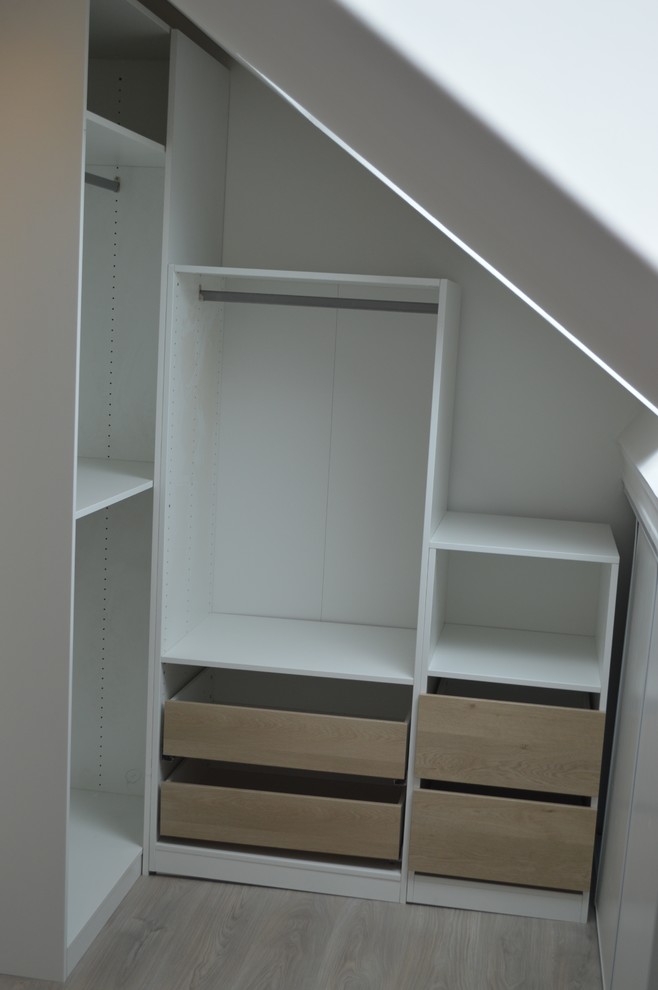 Modelo de vestidor unisex actual de tamaño medio con armarios abiertos, puertas de armario de madera clara, suelo laminado y suelo marrón