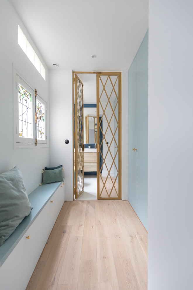 Cette image montre un petit dressing design neutre avec un placard à porte affleurante, des portes de placard bleues, parquet clair et un sol marron.