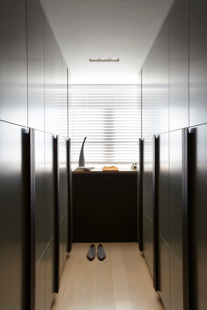 Modelo de armario vestidor unisex contemporáneo grande con armarios con paneles lisos, puertas de armario de madera en tonos medios y suelo de madera clara