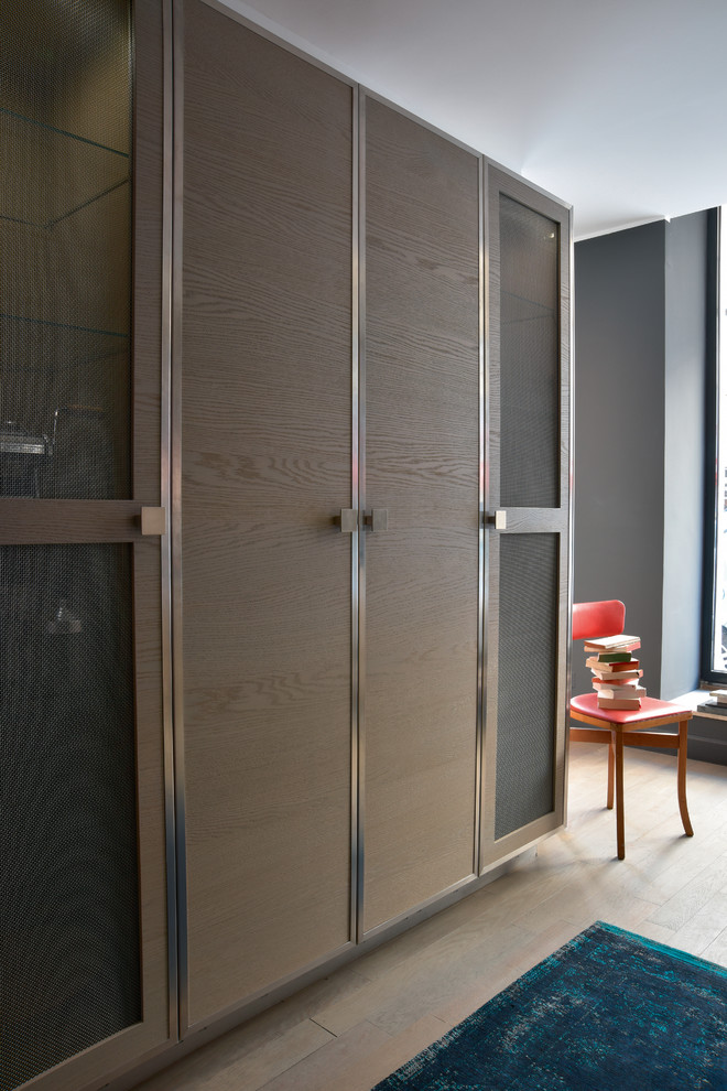 Exemple d'un placard dressing tendance en bois clair de taille moyenne et neutre avec un placard à porte plane et parquet clair.