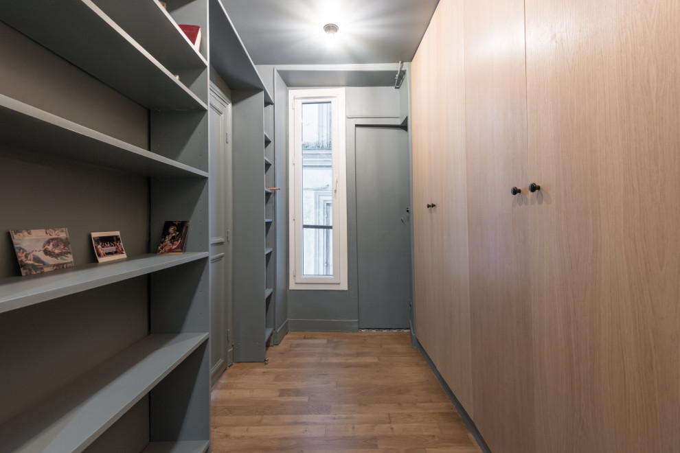 This is an example of a large contemporary dressing room in Paris with beaded cabinets, medium wood cabinets, medium hardwood flooring and brown floors.