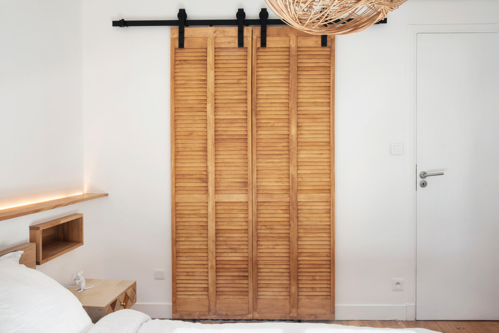 Foto de vestidor unisex urbano pequeño con armarios con puertas mallorquinas, puertas de armario de madera clara, suelo de madera clara y suelo beige