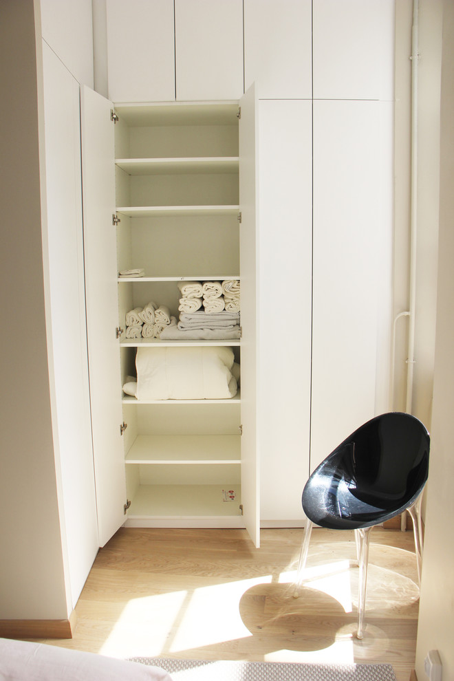 Foto de armario unisex vintage pequeño con armarios con rebordes decorativos, puertas de armario blancas, suelo de madera clara y suelo beige