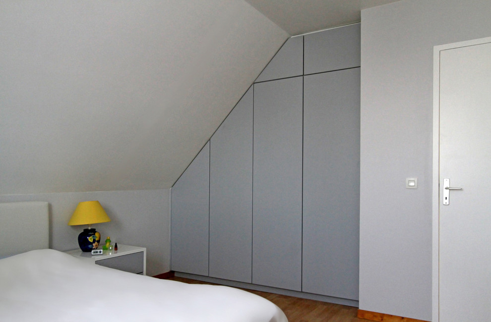 Modelo de armario unisex actual pequeño con puertas de armario grises y suelo de madera clara