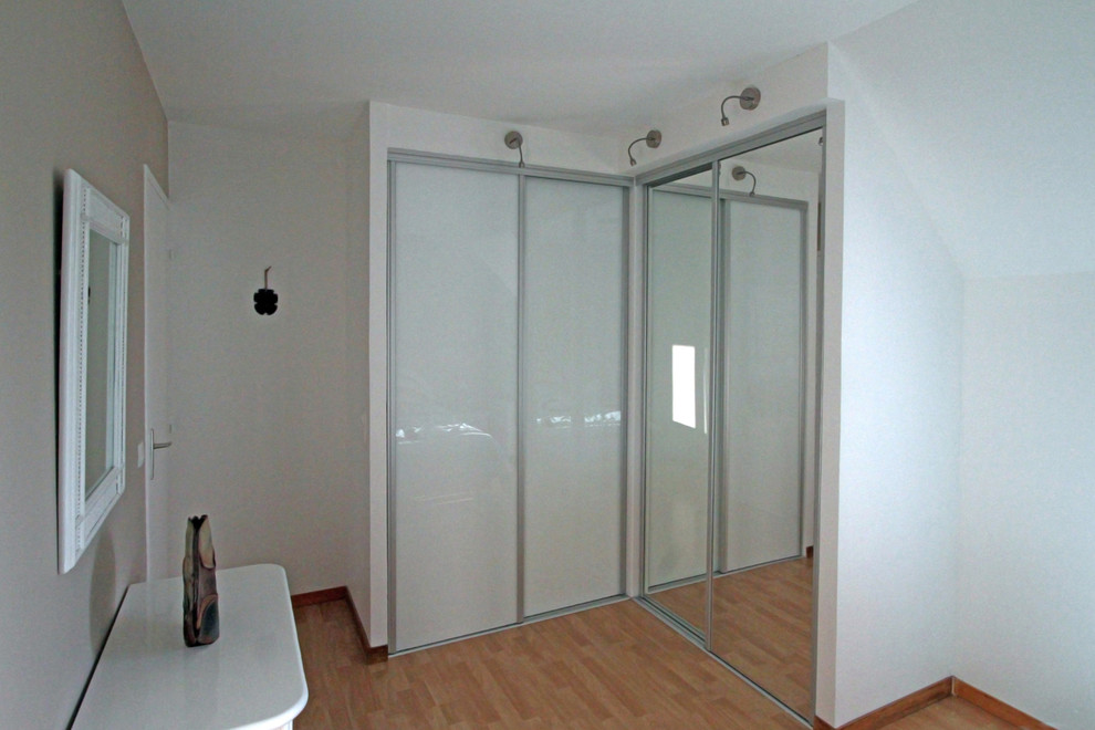 Diseño de armario unisex contemporáneo pequeño con armarios tipo vitrina y suelo de madera clara
