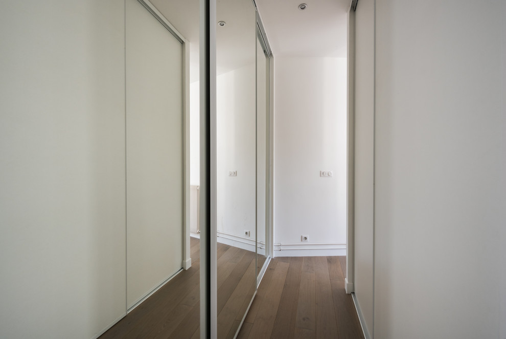 Photo of a medium sized traditional gender neutral walk-in wardrobe in Paris with beaded cabinets, white cabinets, light hardwood flooring and brown floors.