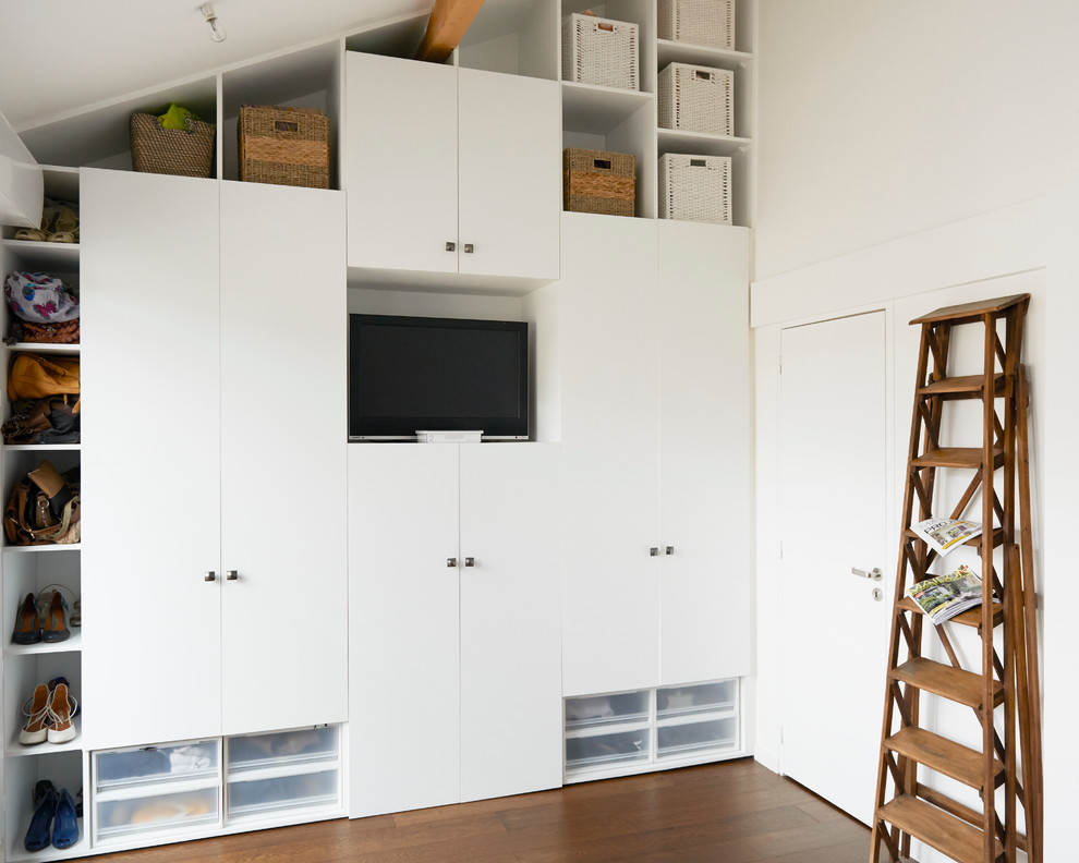Mittelgroßes, EIngebautes, Neutrales Modernes Ankleidezimmer mit braunem Holzboden und weißen Schränken in Paris