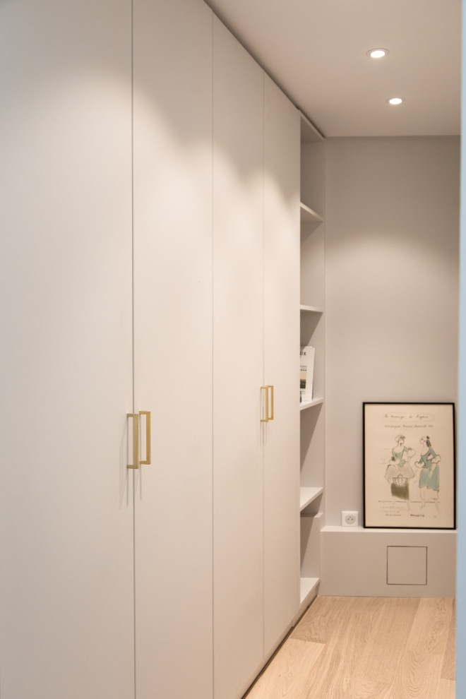 Modelo de armario unisex minimalista de tamaño medio con armarios con rebordes decorativos, puertas de armario grises, suelo de madera clara y suelo beige