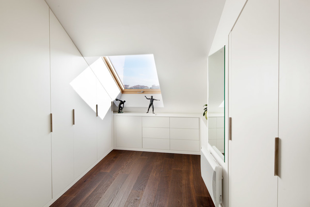 Design ideas for a small contemporary gender neutral dressing room in Nantes with flat-panel cabinets, white cabinets, dark hardwood flooring and brown floors.