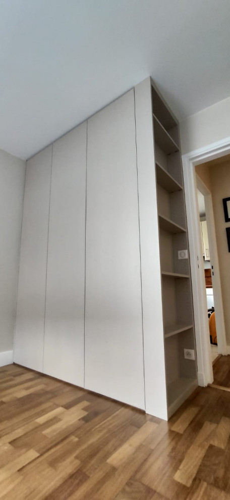 Modelo de armario vestidor unisex clásico renovado de tamaño medio con armarios con rebordes decorativos, puertas de armario beige, suelo de madera oscura y suelo marrón