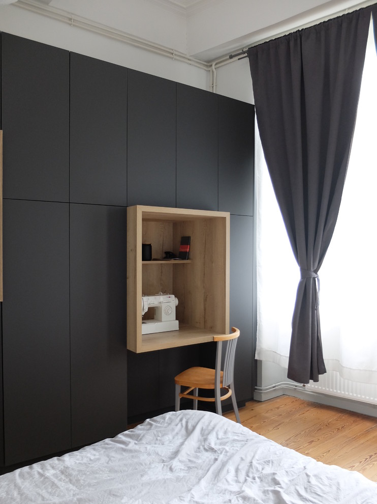 This is an example of a medium sized modern gender neutral standard wardrobe in Grenoble with flat-panel cabinets, grey cabinets, medium hardwood flooring and brown floors.