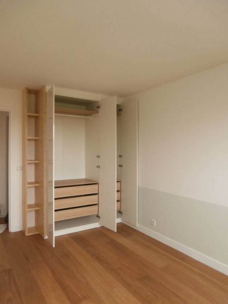 Immagine di un armadio o armadio a muro unisex design di medie dimensioni con pavimento in legno massello medio e ante bianche
