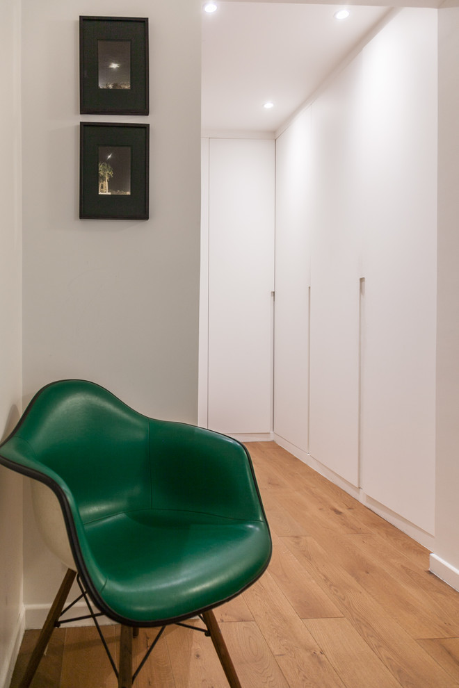 Neutraler Moderner Begehbarer Kleiderschrank mit flächenbündigen Schrankfronten, weißen Schränken, braunem Holzboden und braunem Boden in Paris
