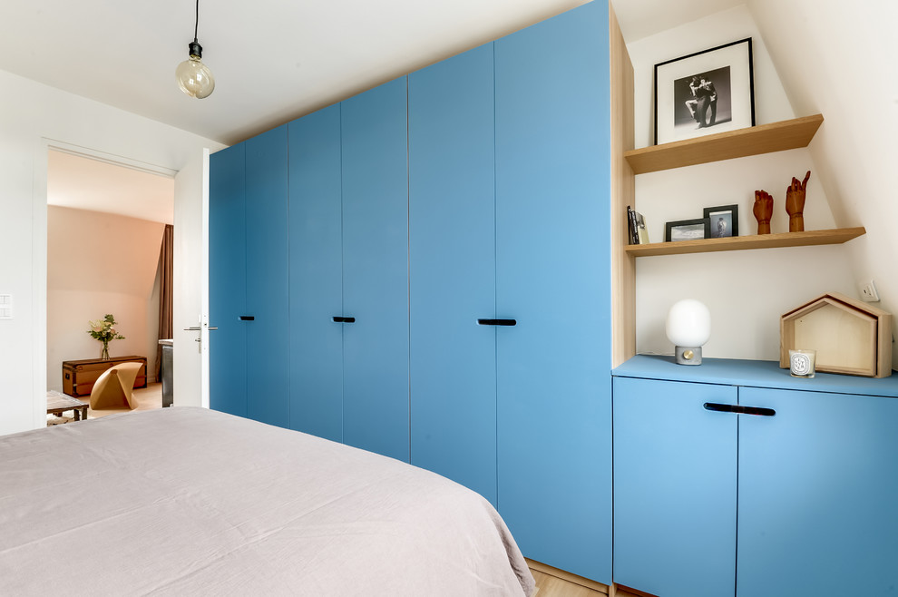 Ejemplo de vestidor unisex actual de tamaño medio con puertas de armario azules y suelo de madera clara