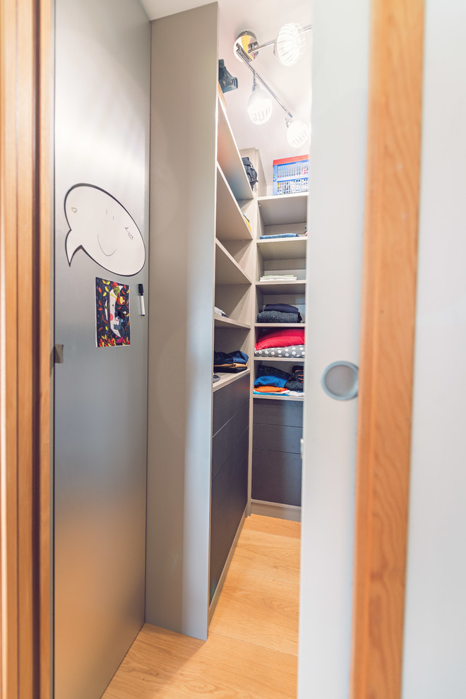 Ejemplo de armario vestidor unisex actual pequeño con armarios abiertos, puertas de armario beige y suelo de madera clara
