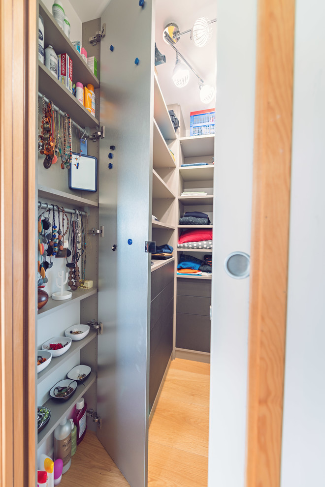 Imagen de armario vestidor unisex contemporáneo pequeño con armarios abiertos, puertas de armario beige y suelo de madera clara