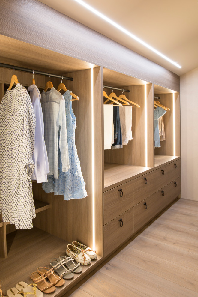 Exemple d'un dressing et rangement méditerranéen pour une femme avec un placard à porte plane, des portes de placard en bois brun, un sol en bois clair, un sol beige et un plafond voûté.